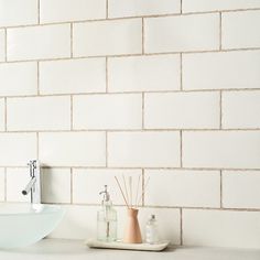 a bathroom sink sitting under a faucet next to a white counter top with soap dispensers on it