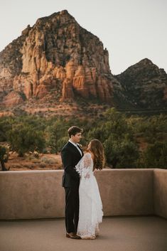 a bride and groom standing in front of a mountain