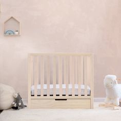 a baby crib next to stuffed animals in a room with pink walls and flooring