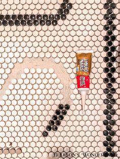 a tube of toothpaste sitting on top of a white and black tiled floor