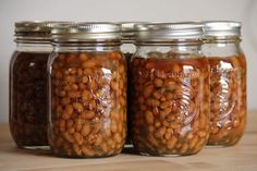 three jars filled with beans sitting on top of a wooden table