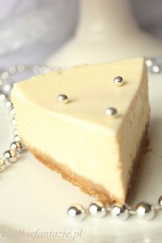 a piece of cheesecake on a white plate with silver beaded chain around it