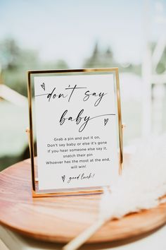 a sign that is on top of a wooden table next to a white and black feather