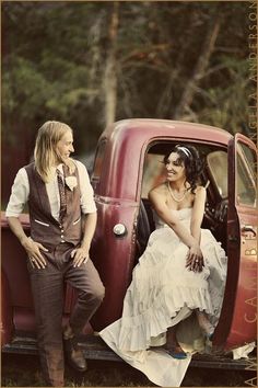 a man and woman sitting in the back of an old red pick up truck together