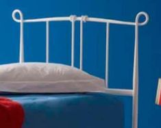 a white metal bed frame against a blue wall with an american flag on it and a red pillow