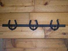 three black metal hooks on a wooden wall