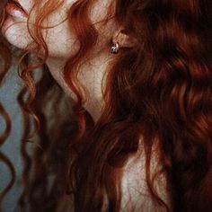 a woman with long red hair is staring into the distance