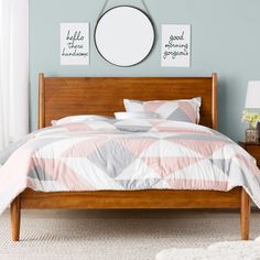 a bed room with a neatly made bed and a round mirror on the wall above it