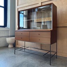 a wooden cabinet sitting next to a toilet in a room