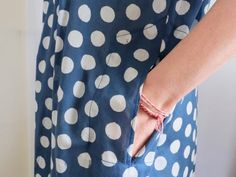 a woman wearing a blue and white polka dot dress with her hands on the pocket