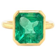 Beautiful hand made ring crafted in 18k yellow gold. The ring highlights one Colombian emerald gemstone that displays an electric green color. The emerald gemstone weighs 6.10 carat and is bezel set in the 18k gold ring. Sharp edges make this gemstone have the appearance of floating on your hand. The green gemstone compliments the yellow gold perfectly. The ring is a size 6, however full sizing is available at your request. The ring weighs 7.4 grams. The ring was crafted in house and is brand ne Luxury Yellow Gold Emerald Solitaire Ring, Luxury Solitaire Emerald Ring In Yellow Gold, Formal Octagon Emerald Ring May Birthstone, Formal Octagon Emerald Ring For May Birthstone, Luxury Green Emerald Ring With Bezel Setting, Fine Jewelry 14k Gold Green Emerald Ring, Luxury Green Ring With Bezel Setting, 14k Gold Green Emerald Ring, 14k Gold Green Emerald Ring, Fine Jewelry