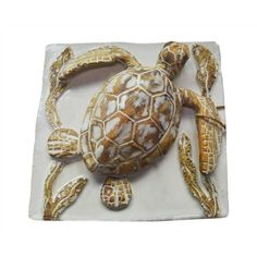 a small ceramic turtle sitting on top of a white tile plate with gold trimmings