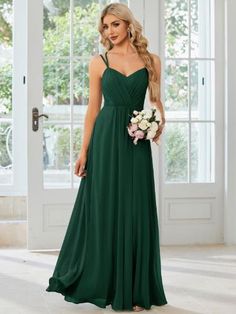 a woman in a long green bridesmaid dress holding a bouquet and posing for the camera