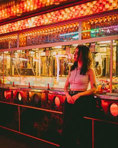 A girl leans against a gaming machine and is illuminated by orange and red lights Fair Aesthetic Friends, Euphoria Lighting, Euphoria Carnival, Carnival Shoot, Curly Hair Brunette, Euphoria Vibe, Park Editorial