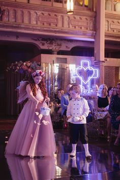 two young children dressed up in fancy clothing and standing on the dance floor at a wedding