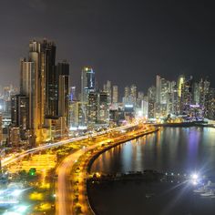 an aerial view of a city at night with lots of lights on the street and water