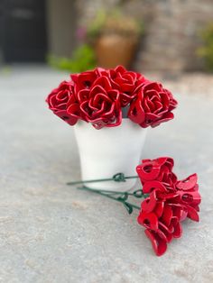 two white vases filled with red flowers on top of a table