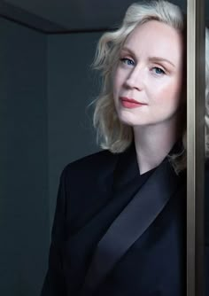 a woman with blonde hair and blue eyes is looking out from behind a glass door