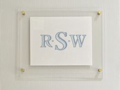 a white and blue wall hanging with the letter r s w on it's side