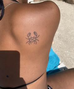 a woman's back with a small crab tattoo on her left side ribcage