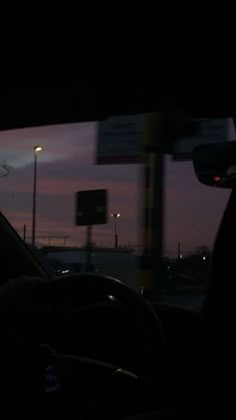 the sun is setting behind some cars on the road in front of an empty parking lot