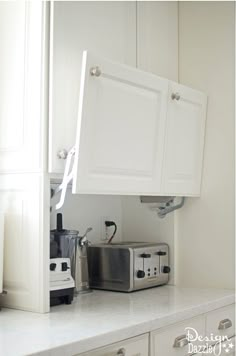 a kitchen with white cabinets and appliances on the counter