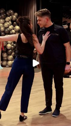 a man and woman dancing on a dance floor with balloons in the air behind them