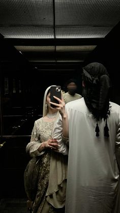 a woman taking a selfie with her cell phone in front of a man dressed as jesus