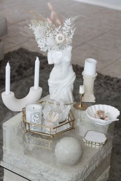 a table topped with candles and vases on top of a white marble slabd surface