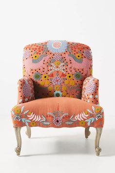 an upholstered chair with floral designs on the armrests and foot rest