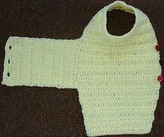 a white knitted sweater with buttons on the front and back, sitting on a brown surface