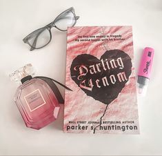 a book, eyeglasses, and lipstick are on the table next to each other