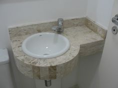 a bathroom sink sitting under a mirror next to a toilet paper dispenser