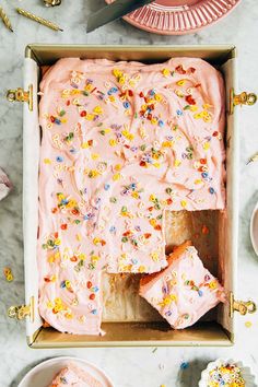 a pink frosted cake with sprinkles in a box on a table