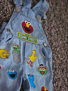 the sesame street denim overalls are decorated with cartoon characters