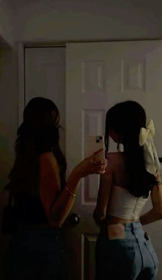 two women standing in front of a mirror brushing their hair