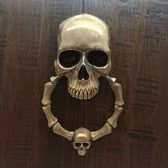 a metal skull mounted to the side of a wooden door with a ring around it