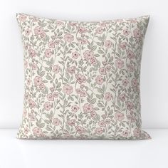 a white pillow with pink flowers and green leaves on the front, sitting on a table