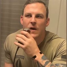 a man brushing his teeth in front of a mirror with an american flag on it