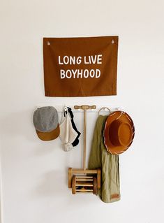 there is a sign that says long live boyhood hanging on the wall next to hats and boots