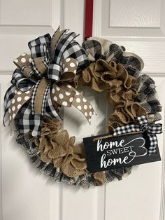 a black and white wreath with the words home sweet home hanging on it's front door