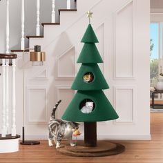 a cat standing next to a christmas tree with two cats in it's holes