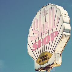 an old shell shop sign on the side of a building with blue sky in the background