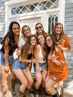 a group of young women standing next to each other in front of a house with the door open