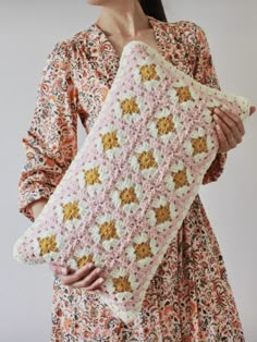 a woman is holding a crocheted pillow in her hands