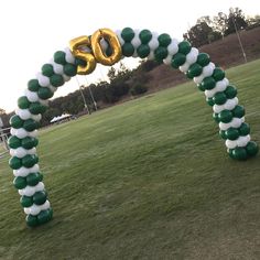 an inflatable balloon arch is decorated with green and white balloons that spell out the number 50