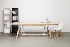 a wooden table sitting in front of a book shelf next to a white chair and bookshelf