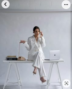 a woman sitting at a desk with a laptop and phone