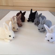 several knitted rabbits sitting on top of a white table next to eachother