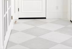 an empty hallway with white walls and black trim on the door, and a checkered floor